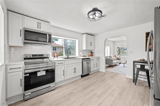 85 Pocantico Ave, Akron, OH 44312 - kitchen with appliances with stainless steel finishes, arched walkways, backsplash, light wood-type flooring, and light countertops