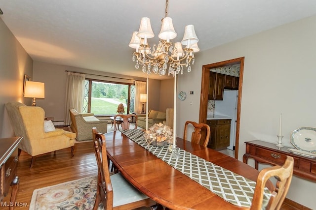 13228 Boulder, Chesterland, OH 44026 - dining room with wood finished floors, a chandelier, and a baseboard heating unit