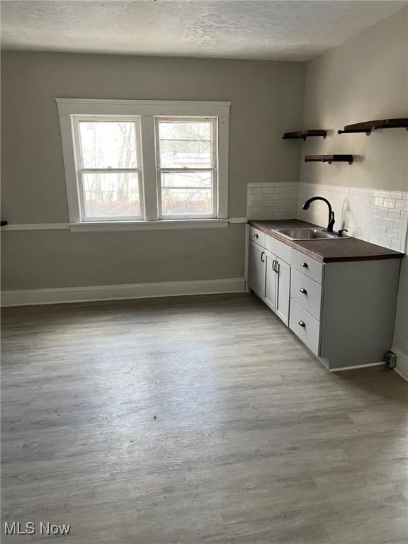 1114 E 64th St, Cleveland, OH 44103 - kitchen with dark countertops, a textured ceiling, light wood-type flooring, backsplash, and open shelves