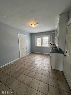 1114 E 64th St, Cleveland, OH 44103 - unfurnished dining area with tile patterned floors and baseboards