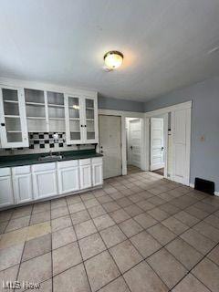 1114 E 64th St, Cleveland, OH 44103 - kitchen with dark countertops, glass insert cabinets, and light tile patterned floors