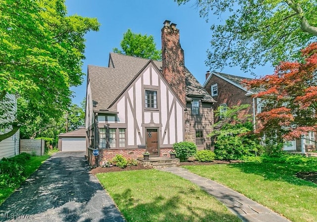 3336 Daleford Rd, Shaker Heights, OH 44120 - view of front facade featuring stucco siding, a detached garage, an outbuilding, a chimney, and a front lawn