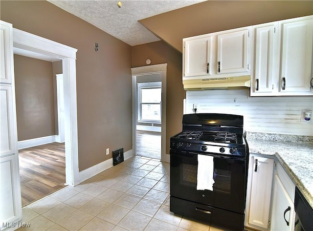 1134 Auburn Pl NW, Canton, OH 44703 - kitchen featuring black gas range oven, under cabinet range hood, light tile patterned floors, white cabinetry, and tasteful backsplash