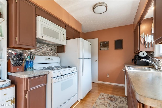 11576 Peach Glen Ave NW, Uniontown, OH 44685 - kitchen with white appliances, tasteful backsplash, light wood-style floors, light countertops, and brown cabinetry