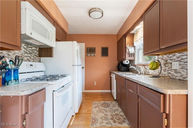 11576 Peach Glen Ave NW, Uniontown, OH 44685 - kitchen with white appliances, light wood-style floors, decorative backsplash, and light countertops
