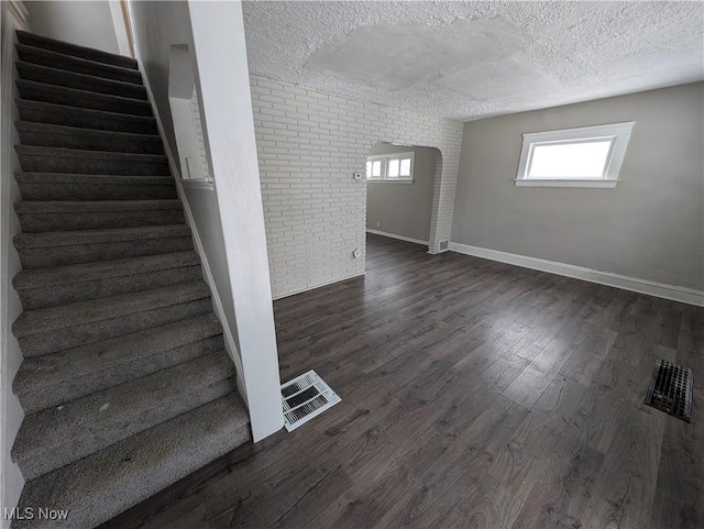3947 W 22nd St, Cleveland, OH 44109 - stairs with a textured ceiling, brick wall, and wood finished floors