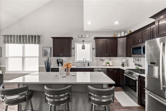 12187 Bexley Dr, Grafton, OH 44044 - kitchen featuring appliances with stainless steel finishes, light countertops, a kitchen island, a kitchen bar, and tasteful backsplash