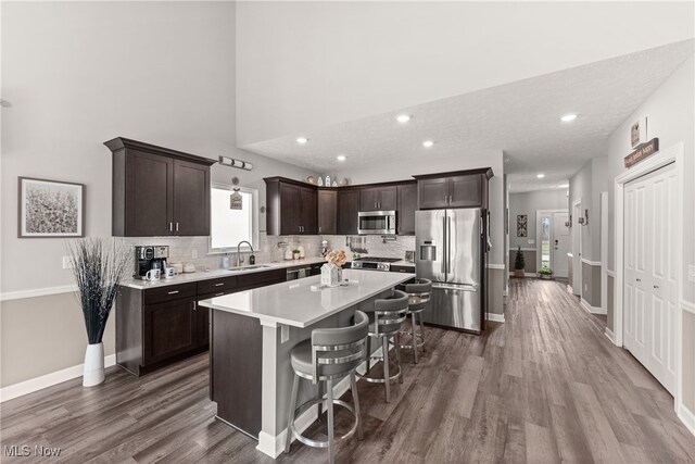 12187 Bexley Dr, Grafton, OH 44044 - kitchen with stainless steel appliances, dark brown cabinetry, dark wood finished floors, a breakfast bar, and recessed lighting