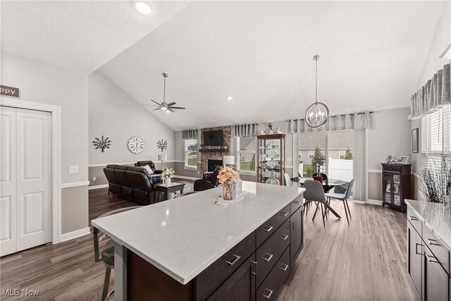 12187 Bexley Dr, Grafton, OH 44044 - kitchen featuring a ceiling fan, a stone fireplace, wood finished floors, light countertops, and a kitchen island