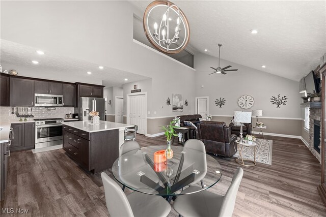 12187 Bexley Dr, Grafton, OH 44044 - dining area with recessed lighting, dark wood finished floors, ceiling fan, a stone fireplace, and high vaulted ceiling