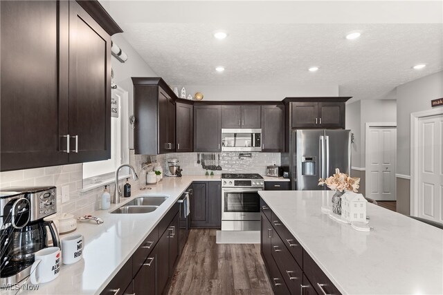 12187 Bexley Dr, Grafton, OH 44044 - kitchen featuring stainless steel appliances, dark brown cabinetry, decorative backsplash, a textured ceiling, and dark wood finished floors