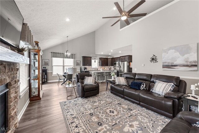 12187 Bexley Dr, Grafton, OH 44044 - living room with a ceiling fan, a stone fireplace, wood finished floors, a textured ceiling, and high vaulted ceiling