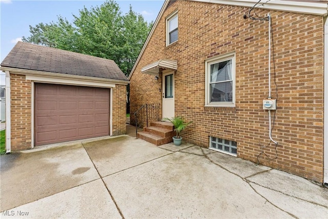 2026 34th St NW, Canton, OH 44709 - view of front facade featuring driveway, brick siding, an outbuilding, a detached garage, and a shingled roof