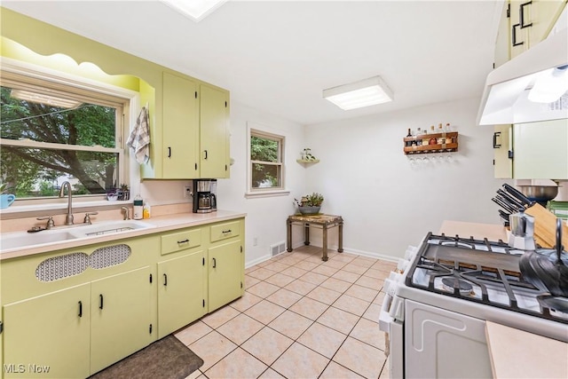 2026 34th St NW, Canton, OH 44709 - kitchen with under cabinet range hood, gas range gas stove, light countertops, light tile patterned flooring, and yellow cabinetry