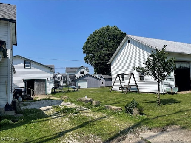 320 E Union Ave, West Lafayette, OH 43845 - view of grassy yard featuring an outdoor structure, a trampoline, and a garage