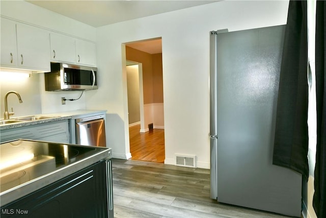 2803 Brunswick Rd, Youngstown, OH 44511 - kitchen featuring stainless steel appliances, white cabinetry, light wood finished floors, and light countertops