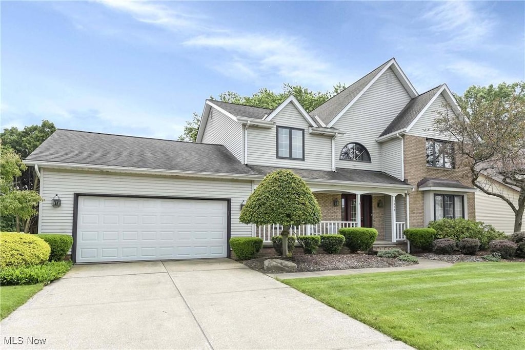 2850 Wynde Tree Dr, Seven Hills, OH 44131 - traditional home with a porch, concrete driveway, a garage, a front lawn, and brick siding