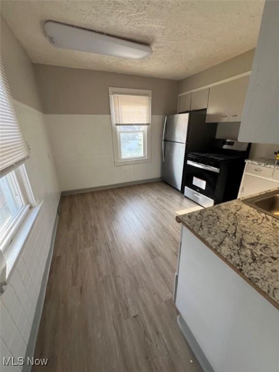 836 E 236th St, Euclid, OH 44123 - kitchen featuring appliances with stainless steel finishes, light wood-type flooring, a textured ceiling, and light stone counters