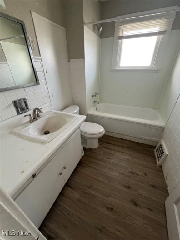 836 E 236th St, Euclid, OH 44123 - full bath featuring wood finished floors, vanity, tub / shower combination, and tile walls