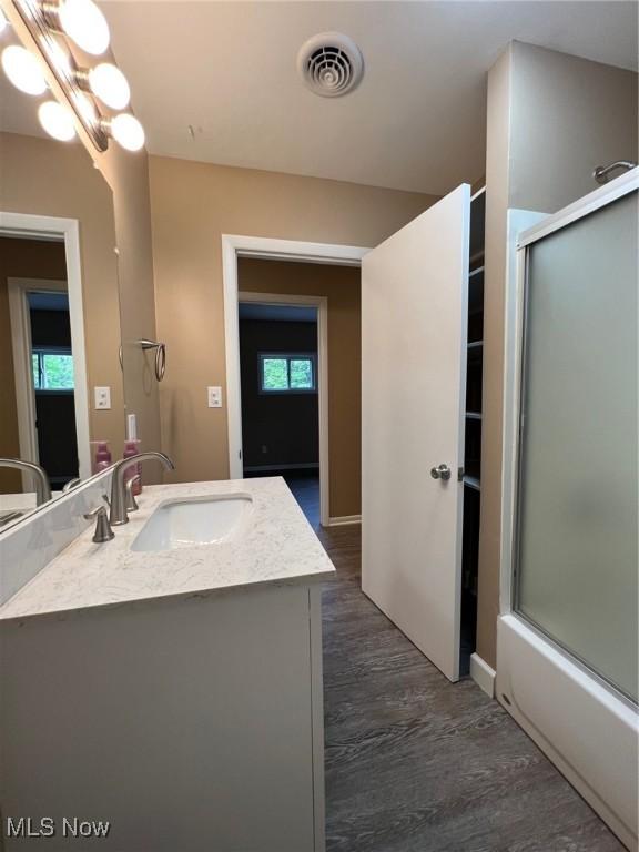 213 Turner Dr, Chardon, OH 44024 - bathroom featuring vanity, healthy amount of natural light, wood finished floors, and bath / shower combo with glass door