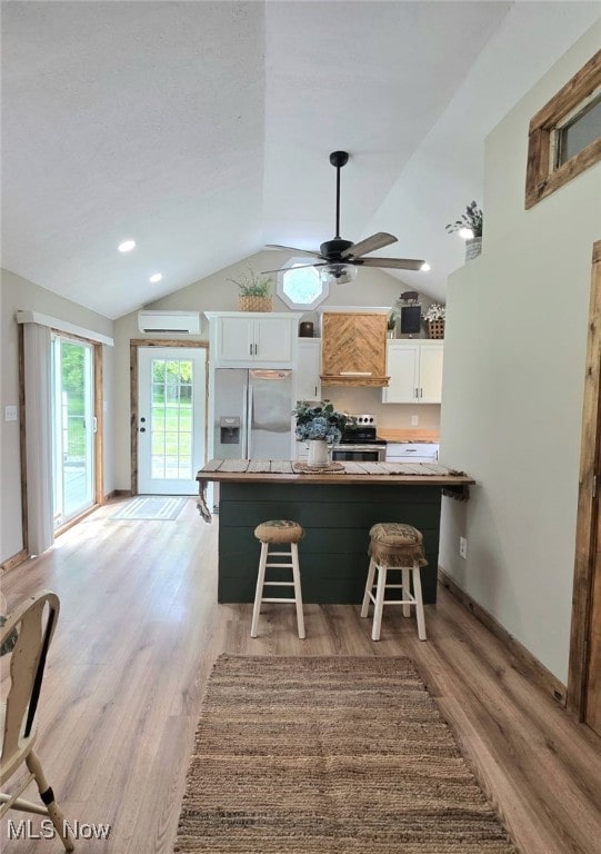 12779 State Route 700, Hiram, OH 44234 - kitchen featuring appliances with stainless steel finishes, an AC wall unit, a breakfast bar area, white cabinets, and vaulted ceiling