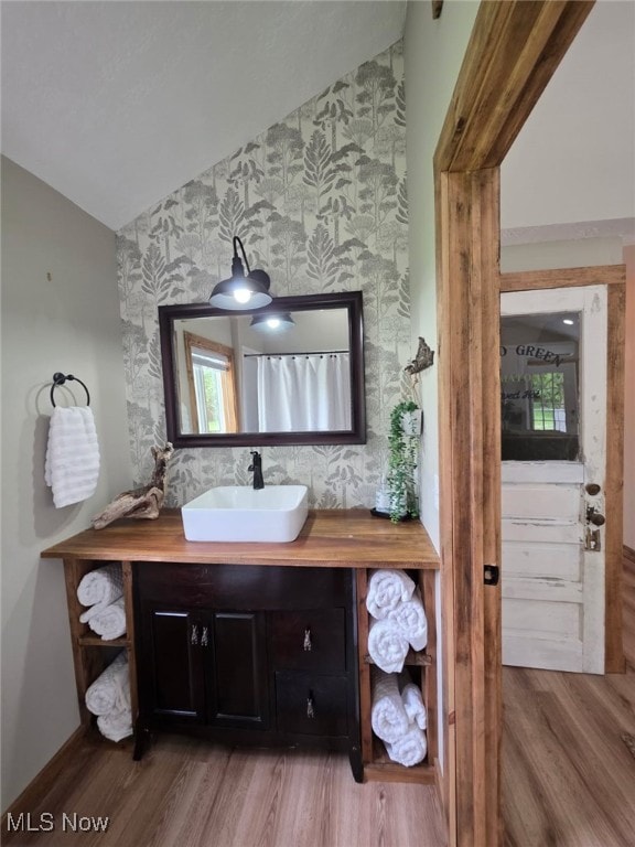12779 State Route 700, Hiram, OH 44234 - bathroom featuring wallpapered walls, vaulted ceiling, vanity, wood finished floors, and an accent wall
