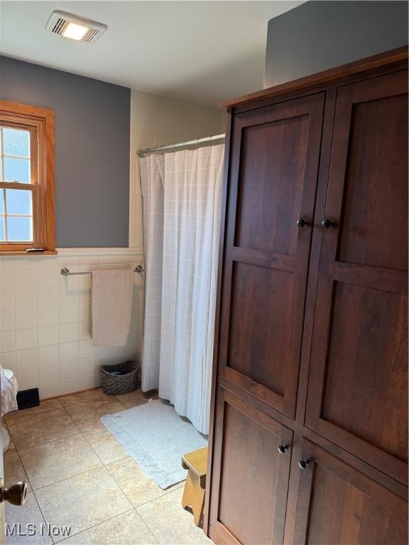 203 Park Ave, Middlebourne, WV 26149 - bathroom featuring tile walls, tile patterned flooring, curtained shower, and a wainscoted wall