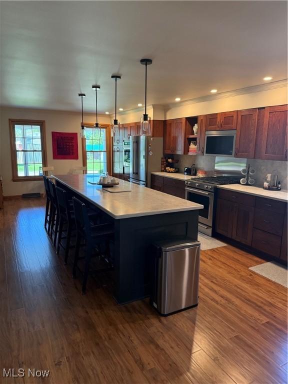 203 Park Ave, Middlebourne, WV 26149 - kitchen featuring appliances with stainless steel finishes, dark wood-style flooring, light countertops, open shelves, and a breakfast bar