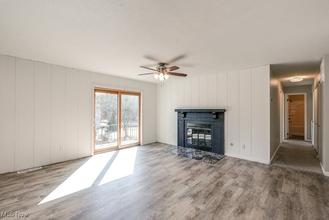 2401 Island Dr Unit 20D, Uniontown, OH 44685 - unfurnished living room featuring wood finished floors, a ceiling fan, a fireplace with flush hearth, and a decorative wall