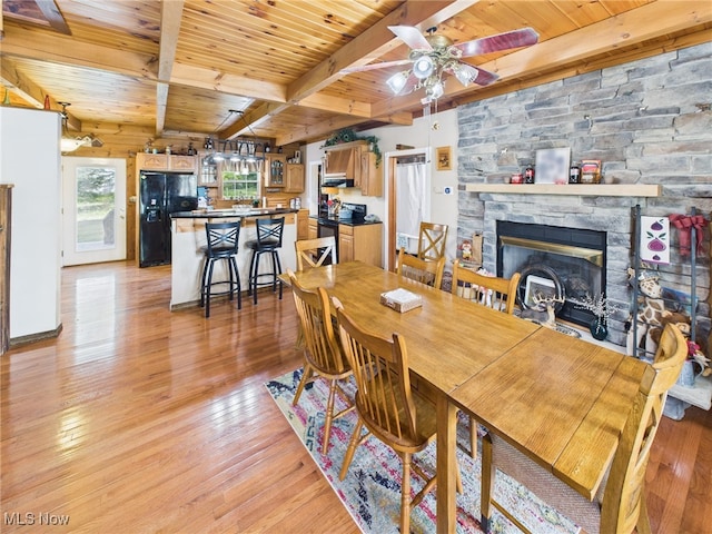 9246 State Route 555, Cutler, OH 45724 - dining area featuring a wooden ceiling with exposed beams, light wood-type flooring, a stone fireplace, and a ceiling fan