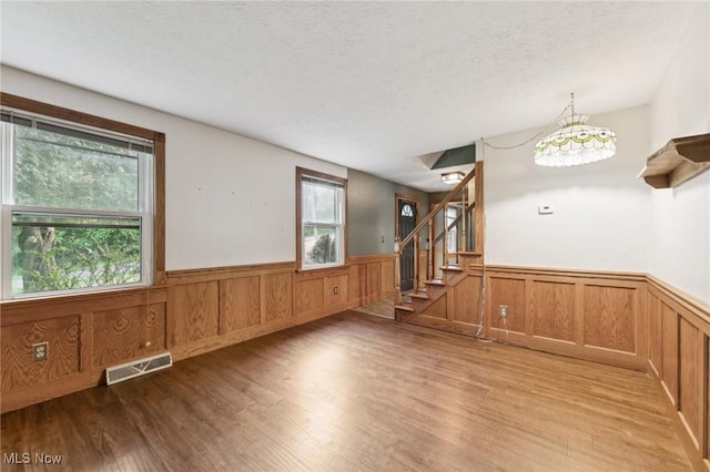 3594 Heckman St NW, Uniontown, OH 44685 - spare room featuring wainscoting, wood finished floors, stairs, a textured ceiling, and a chandelier