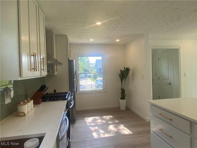 109 Avalon Ave, Bedford, OH 44146 - kitchen featuring under cabinet range hood, appliances with stainless steel finishes, light wood-style floors, backsplash, and recessed lighting