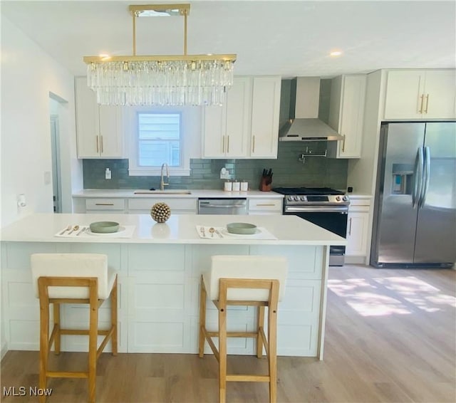 109 Avalon Ave, Bedford, OH 44146 - kitchen with stainless steel appliances, wall chimney exhaust hood, light wood-style floors, and decorative backsplash