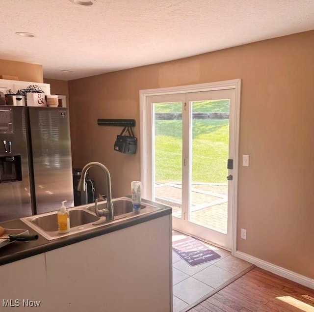 1310 Oxbow Rd, Belpre, OH 45714 - kitchen with stainless steel fridge, white cabinetry, a textured ceiling, and light wood-style flooring