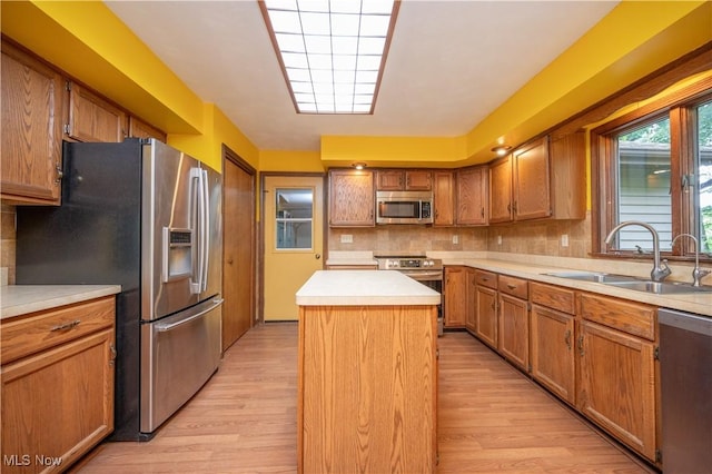 3355 Waterford Rd, New Waterford, OH 44445 - kitchen with appliances with stainless steel finishes, light wood-style floors, a kitchen island, decorative backsplash, and brown cabinetry