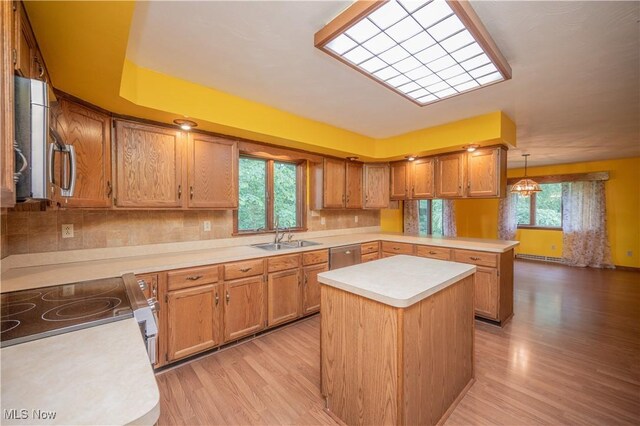 3355 Waterford Rd, New Waterford, OH 44445 - kitchen featuring a peninsula, appliances with stainless steel finishes, light countertops, light wood-style flooring, and brown cabinetry