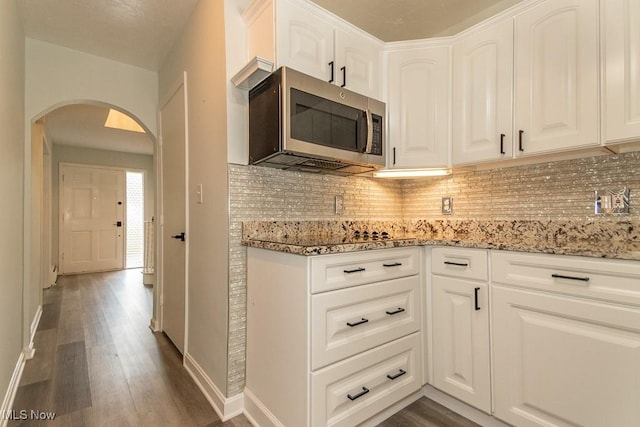 3 Meadowlawn Dr Unit 13, Mentor, OH 44060 - kitchen featuring stainless steel microwave, arched walkways, light stone countertops, and tasteful backsplash