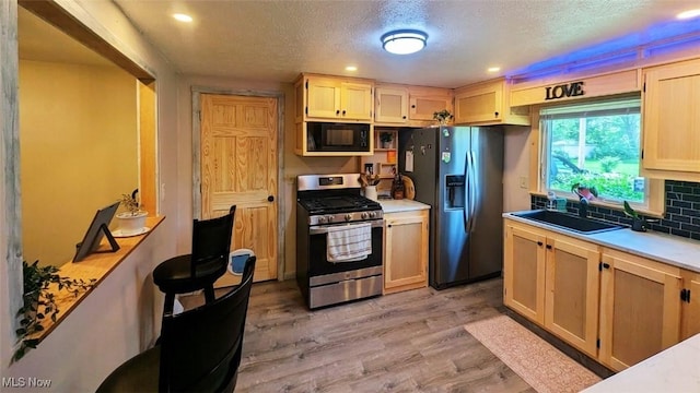 6323 Olive Ave, North Ridgeville, OH 44039 - kitchen featuring stainless steel appliances, light wood finished floors, light countertops, a textured ceiling, and backsplash