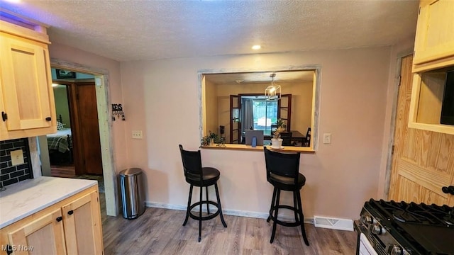 6323 Olive Ave, North Ridgeville, OH 44039 - kitchen with wood finished floors, a textured ceiling, light countertops, light brown cabinetry, and a breakfast bar