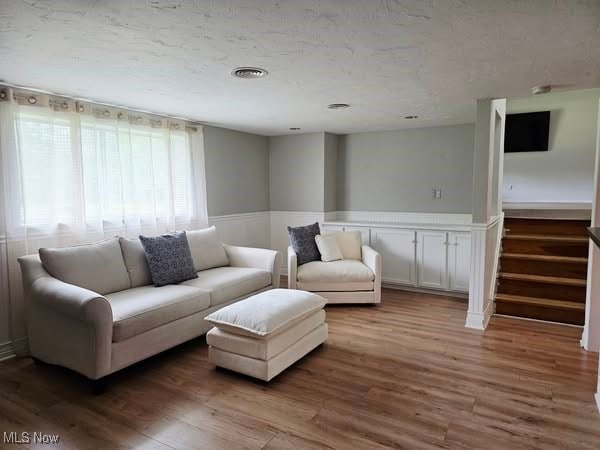 7957 Pamela Dr, North Royalton, OH 44133 - living area with wood finished floors, a wainscoted wall, stairway, and a textured ceiling