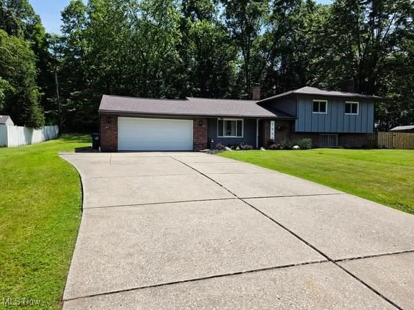 7957 Pamela Dr, North Royalton, OH 44133 - tri-level home featuring an attached garage, driveway, brick siding, board and batten siding, and a chimney