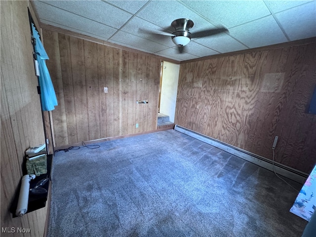 1605 Gihon Rd, Parkersburg, WV 26101 - carpeted empty room featuring ceiling fan, a baseboard radiator, wood walls, and a drop ceiling