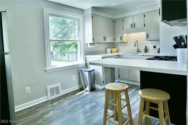 437 Hazel St, Girard, OH 44420 - kitchen with light countertops, decorative backsplash, a kitchen breakfast bar, wood finished floors, and cooktop