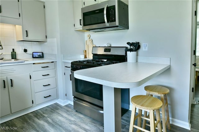 437 Hazel St, Girard, OH 44420 - kitchen with stainless steel appliances, a kitchen breakfast bar, dark wood-style floors, light countertops, and a peninsula