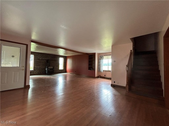 14260 Canaan Center Rd, Creston, OH 44217 - unfurnished living room featuring wood finished floors, stairs, brick wall, and a wood stove