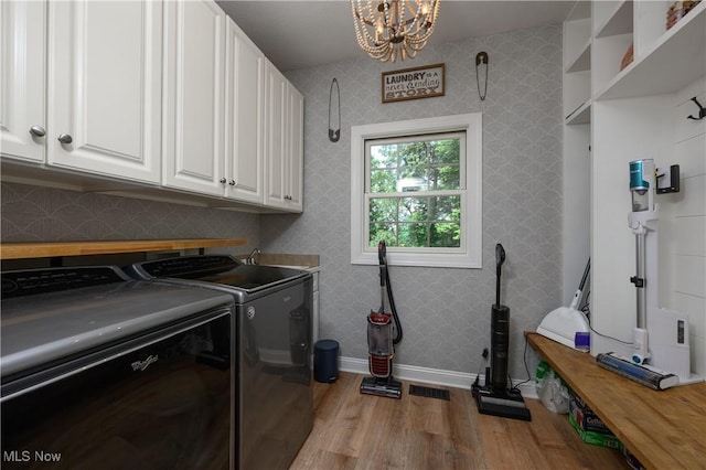 3595 Vineyard Ave NW, Canton, OH 44708 - washroom with cabinet space, light wood-type flooring, washing machine and dryer, a chandelier, and wallpapered walls