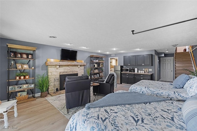4613 Compass Rose Unit 11, Vermilion, OH 44089 - bedroom featuring freestanding refrigerator, a fireplace, light wood-style flooring, and recessed lighting