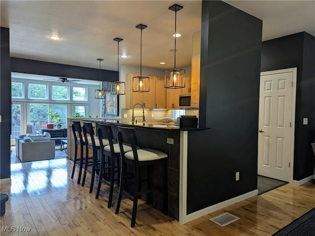1949 Columbus Rd, Cleveland, OH 44113 - kitchen with stainless steel microwave, ceiling fan, light wood finished floors, backsplash, and recessed lighting