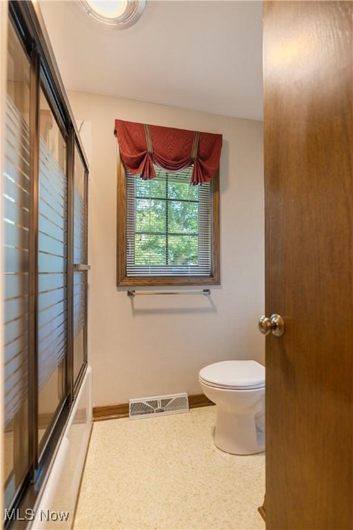221 Winston Ave NE, North Canton, OH 44720 - bathroom featuring toilet and bath / shower combo with glass door