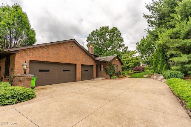 221 Winston Ave NE, North Canton, OH 44720 - view of side of home with brick siding, concrete driveway, a garage, and a chimney